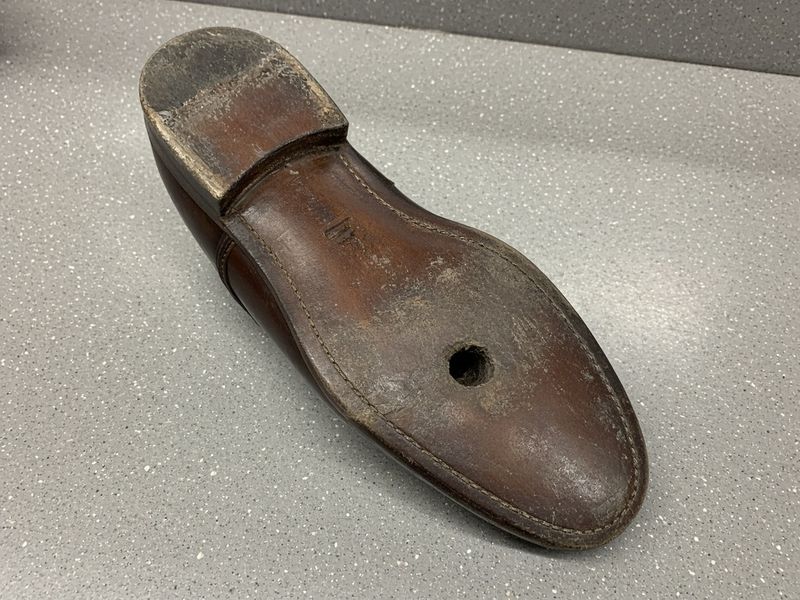 Dress shoe sole, before: worn-down heel and a hole through the leather sole